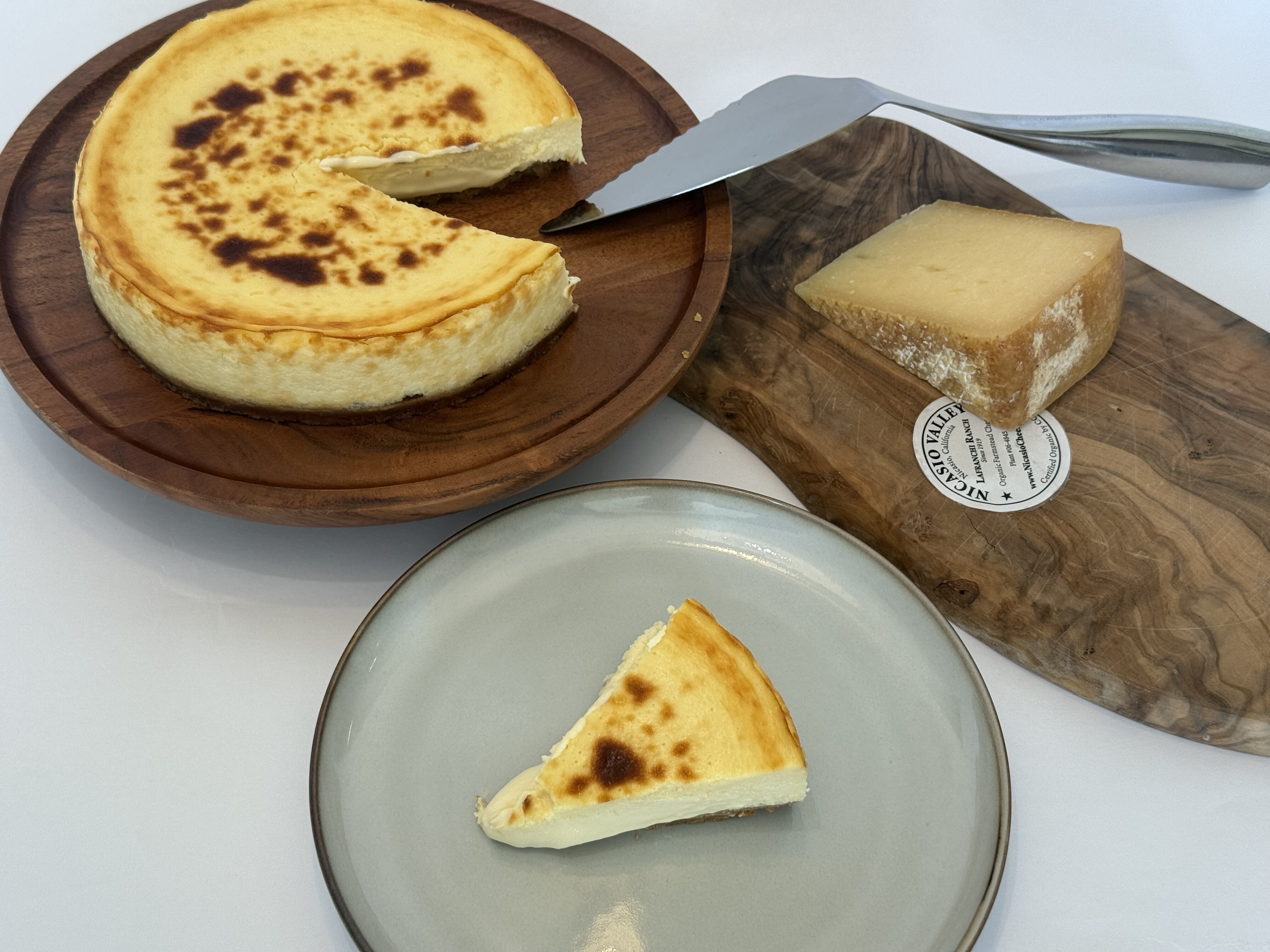 Madrid-style tarta de queso with a slice plated beside cheese.